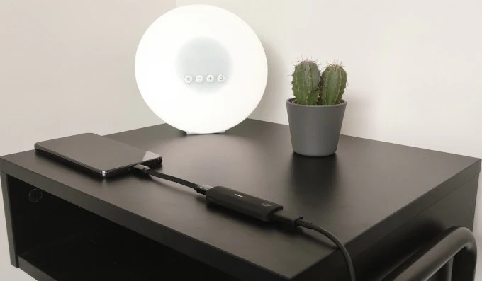 Liion Power's Leo adapter plugged into a cellphone while it charges on a nightstand.